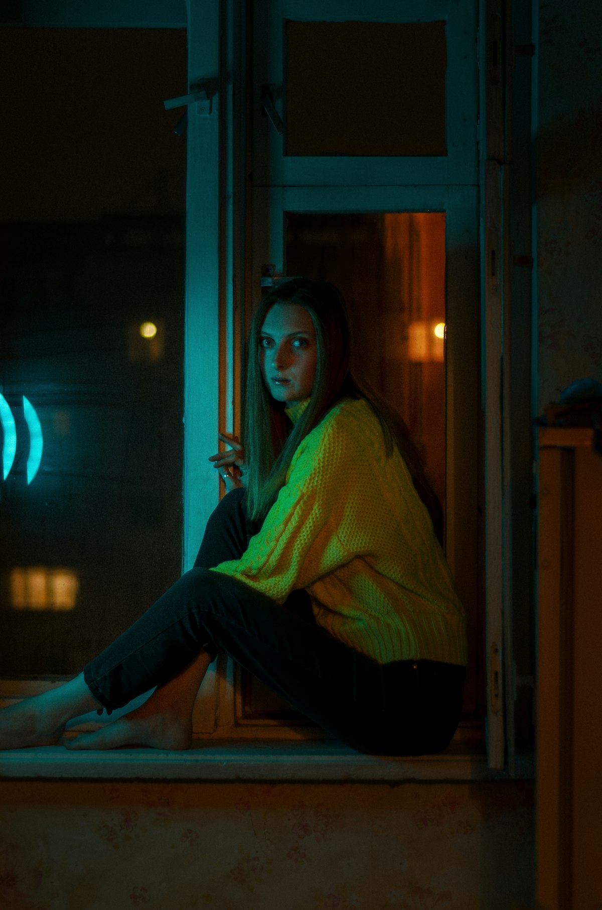 Woman sitting in contemplative pose by a window in soft light