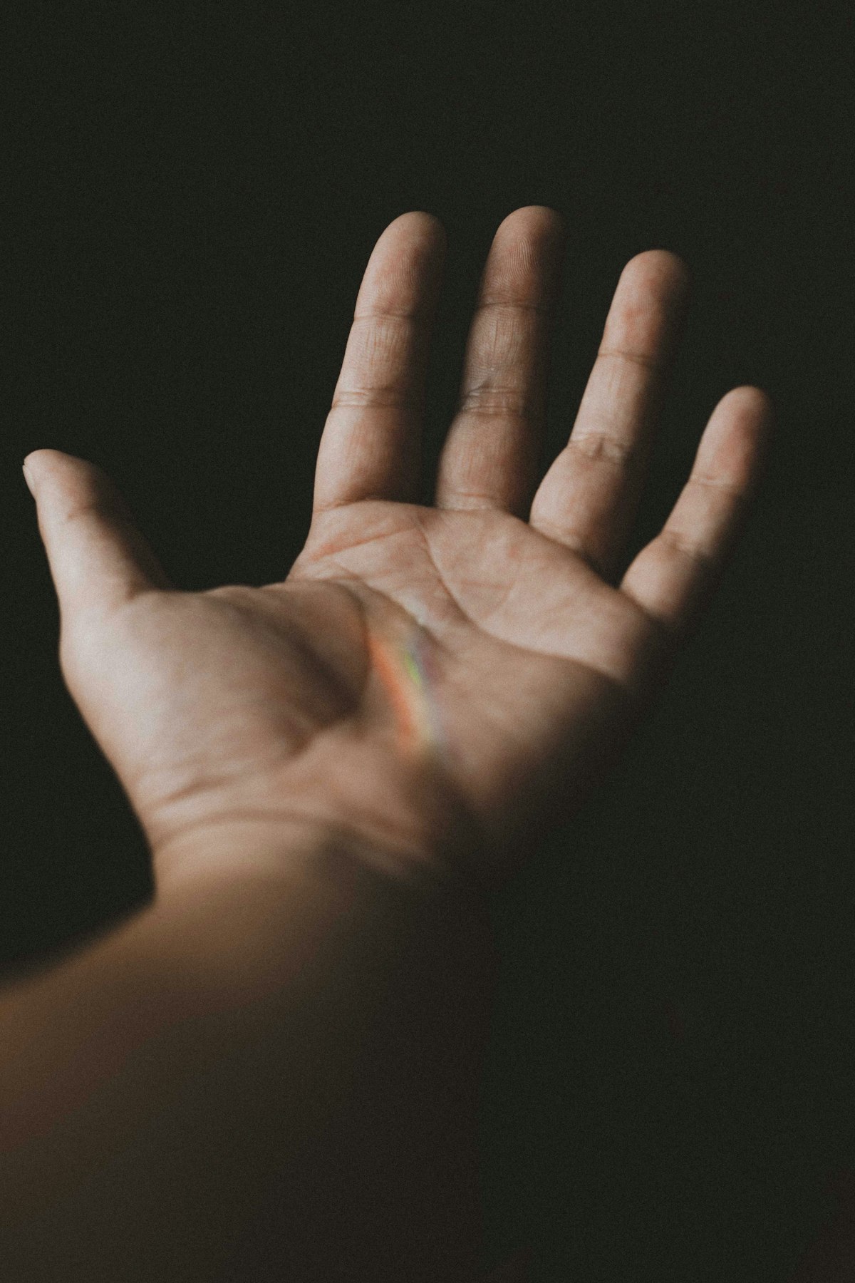 Hands illuminated by colorful rainbow prism light