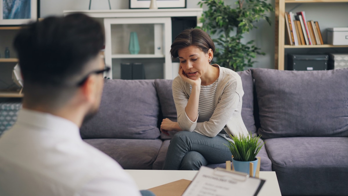 A woman and a man sitting on a couch, engaged in a warm and professional conversation