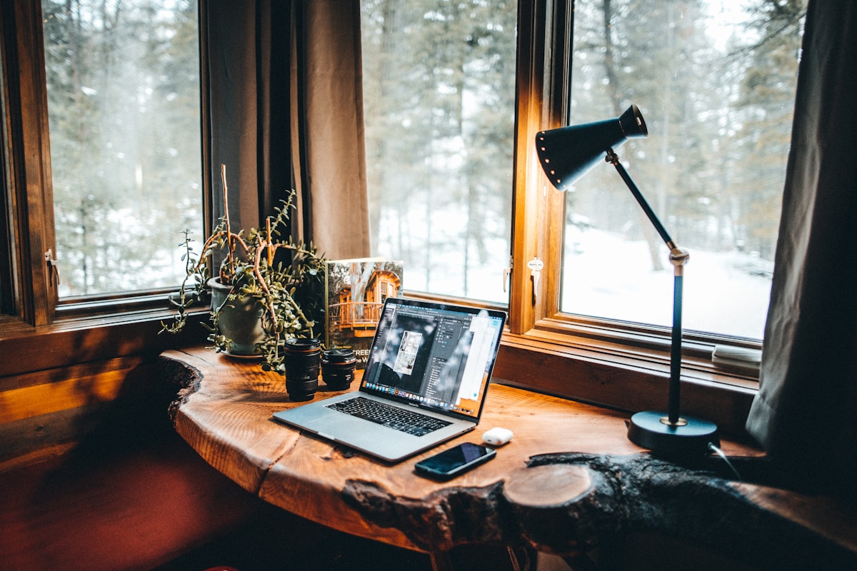 A warm, glowing desk lamp next to a laptop in a cozy rustic workspace