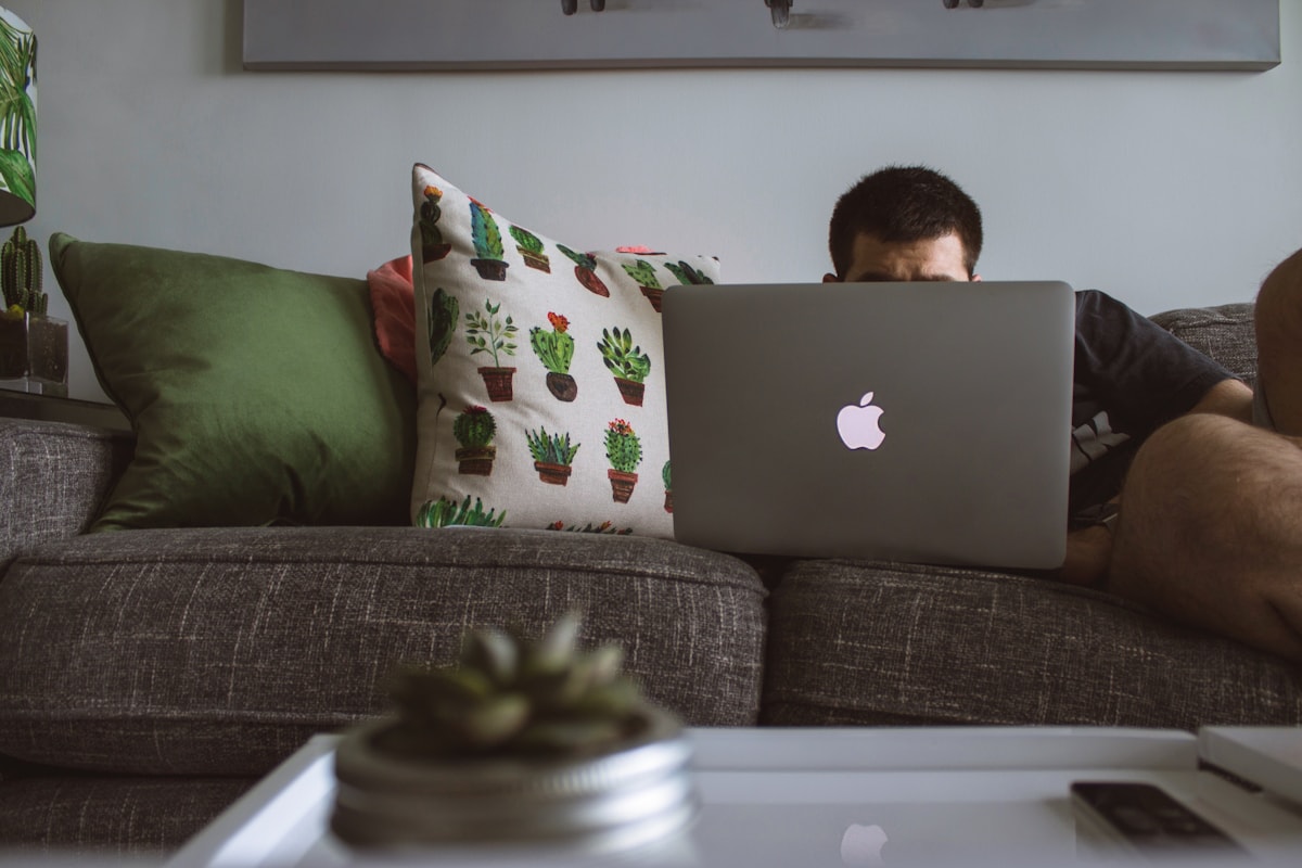 Person relaxed on a couch working on a laptop in a comfortable home setting